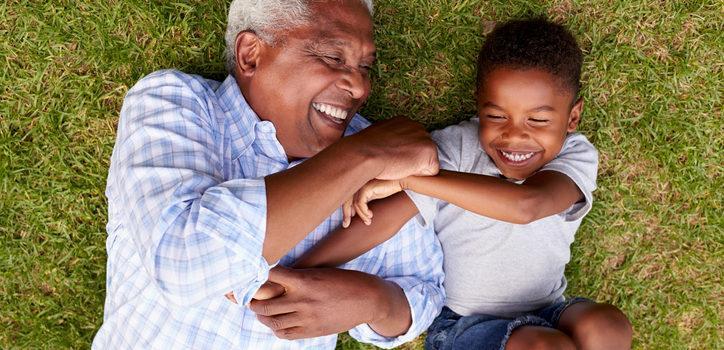 Grandfather and grandson play lying on grass, aerial view