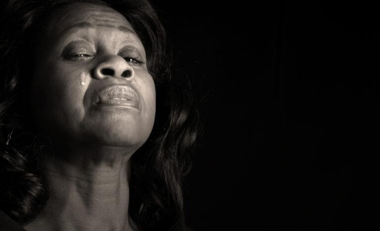 A woman with a long hair crying in the dark